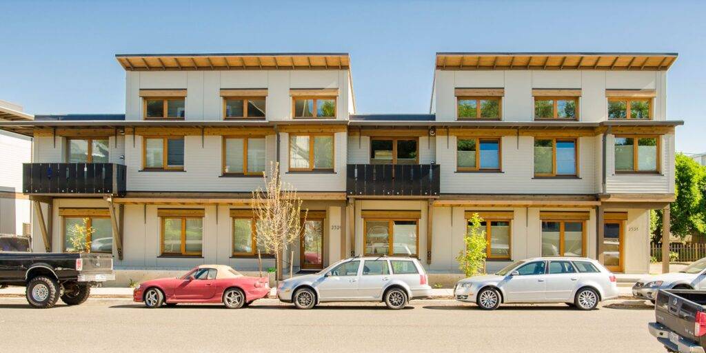 Street view of Ankeny Row development in Portland, Oregon with several townhomes and parked cars.
