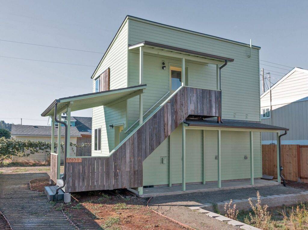 Exterior of duplex unit at C St development in Springfield OR with staircase leading to second floor unit and cover for bike parking.