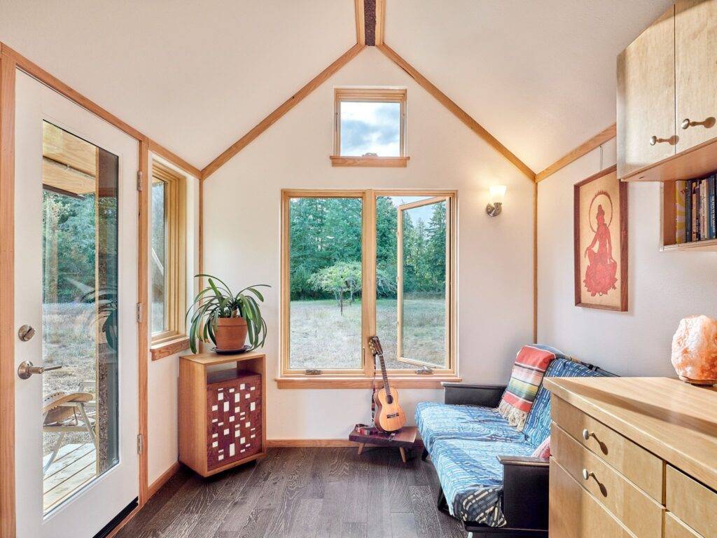 Seating area in tiny house barnraising project with large windows and views of outdoors.