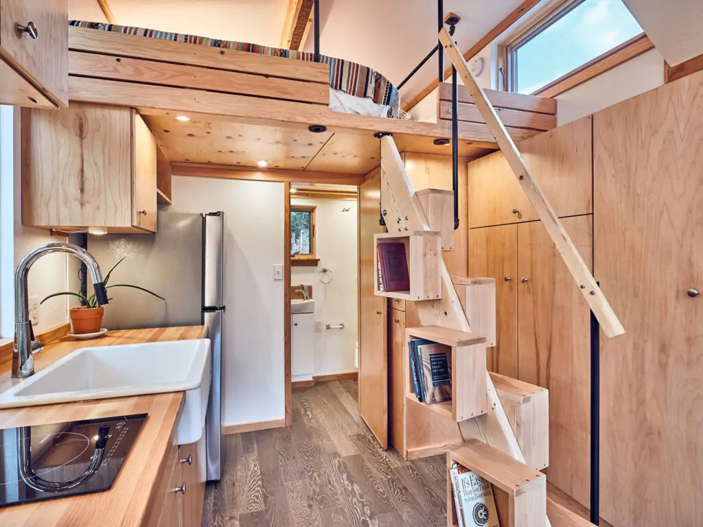 Interior of tiny house barnraising project featuring innovative rotatable staircase design with built-in storage.