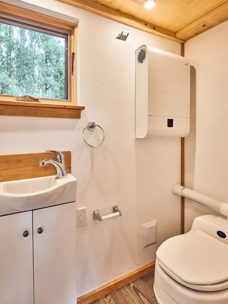 Restroom of tiny house barnraising project featuring composting toilet and energy efficient ventilation system.